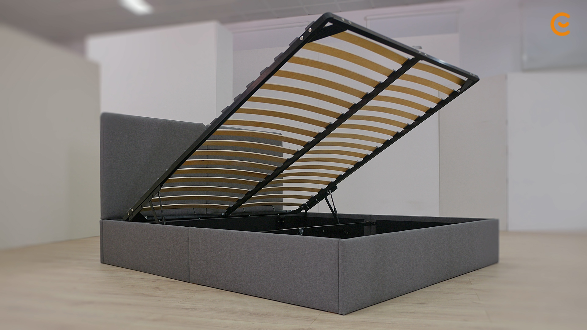 Letto contenitore grigio con rete sollevata che mostra lo spazio di stoccaggio sottostante.