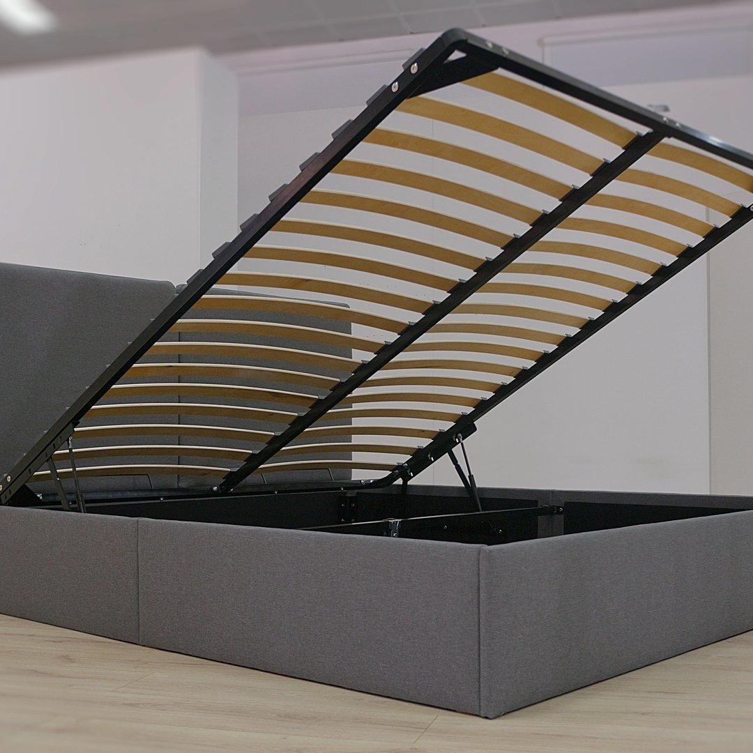Letto contenitore grigio con rete sollevata che mostra lo spazio di stoccaggio sottostante.