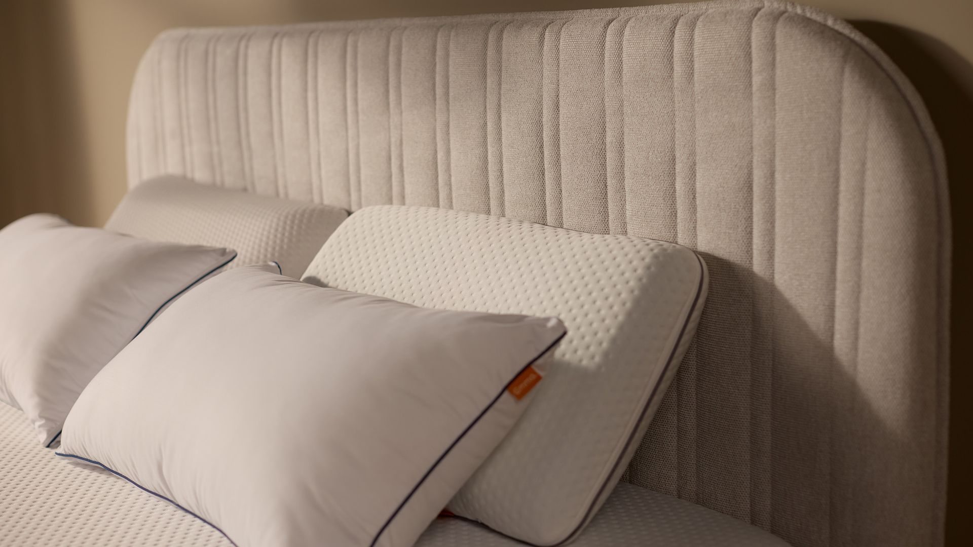 Nahaufnahme des gepolsterten Kopfteils mit vertikaler Kanalsteppung und sauber verarbeiteten Nähten, mit Kissen.