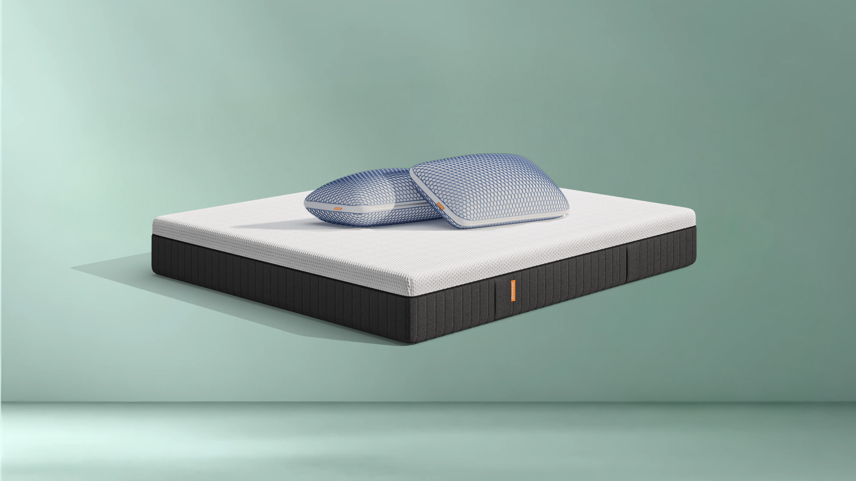 Matelas avec deux oreillers posés dessus sur un fond gris clair.