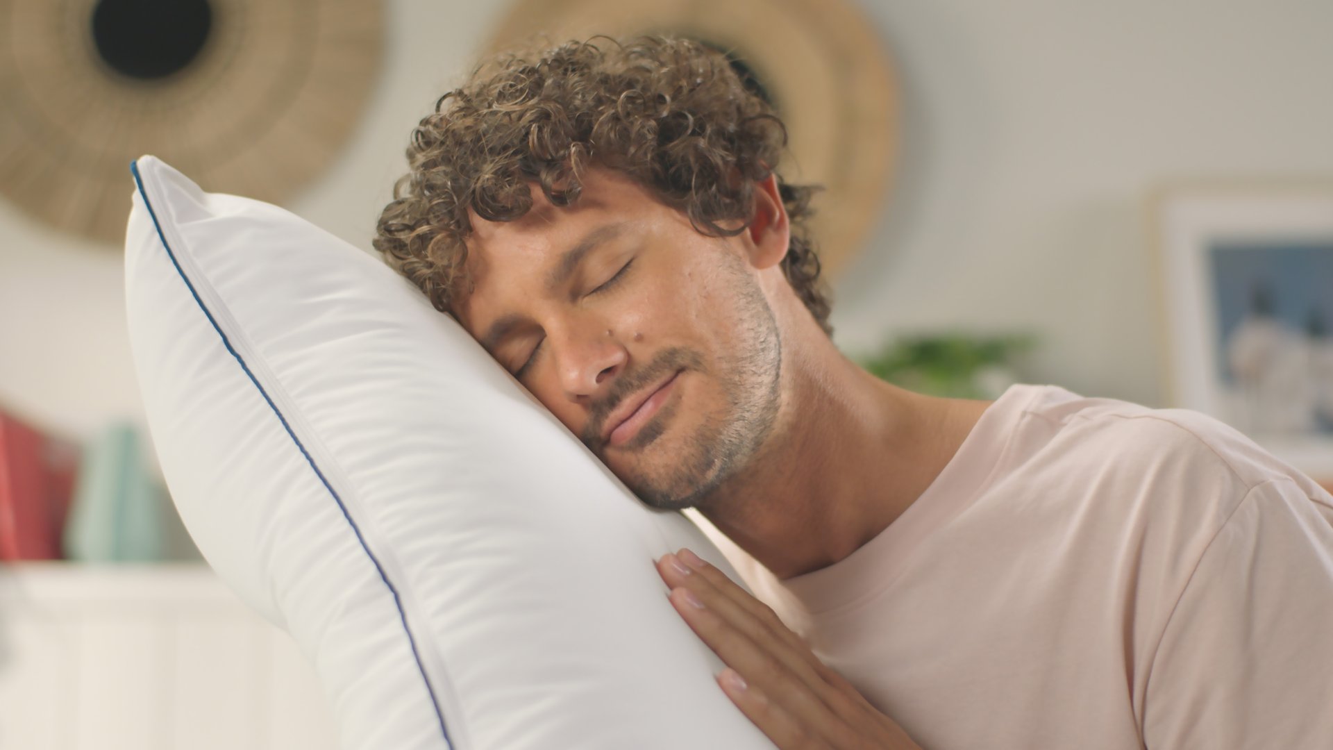 Personne reposant la tête sur l’Oreiller Nuage blanc avec passepoil bleu, expression détendue.