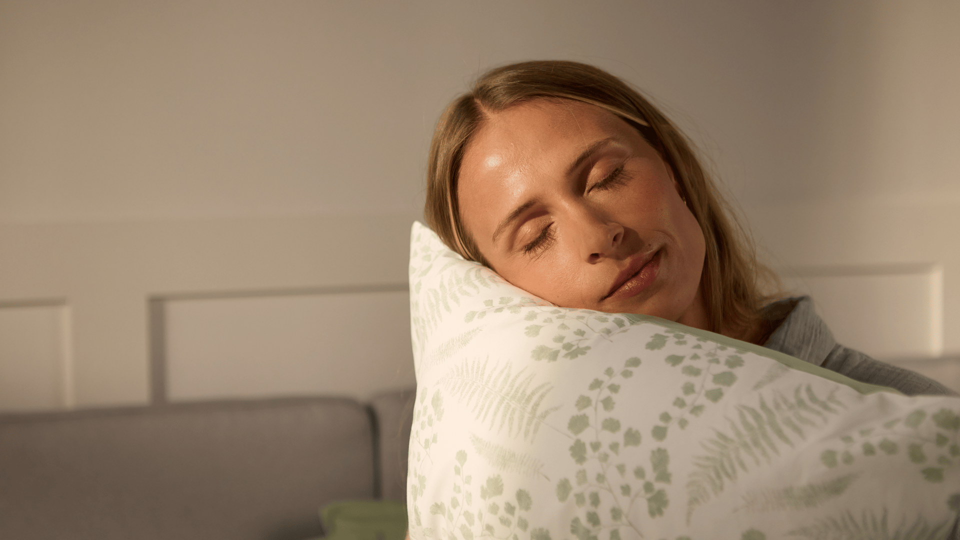 Frau liegt im Bett und hält ein Kissen.
