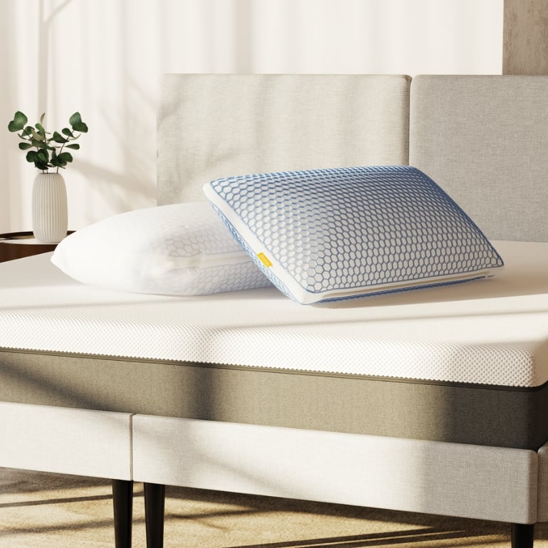 2 almohadas viscoelásticas elite una con funda y la otra sin funda encima de la cama 