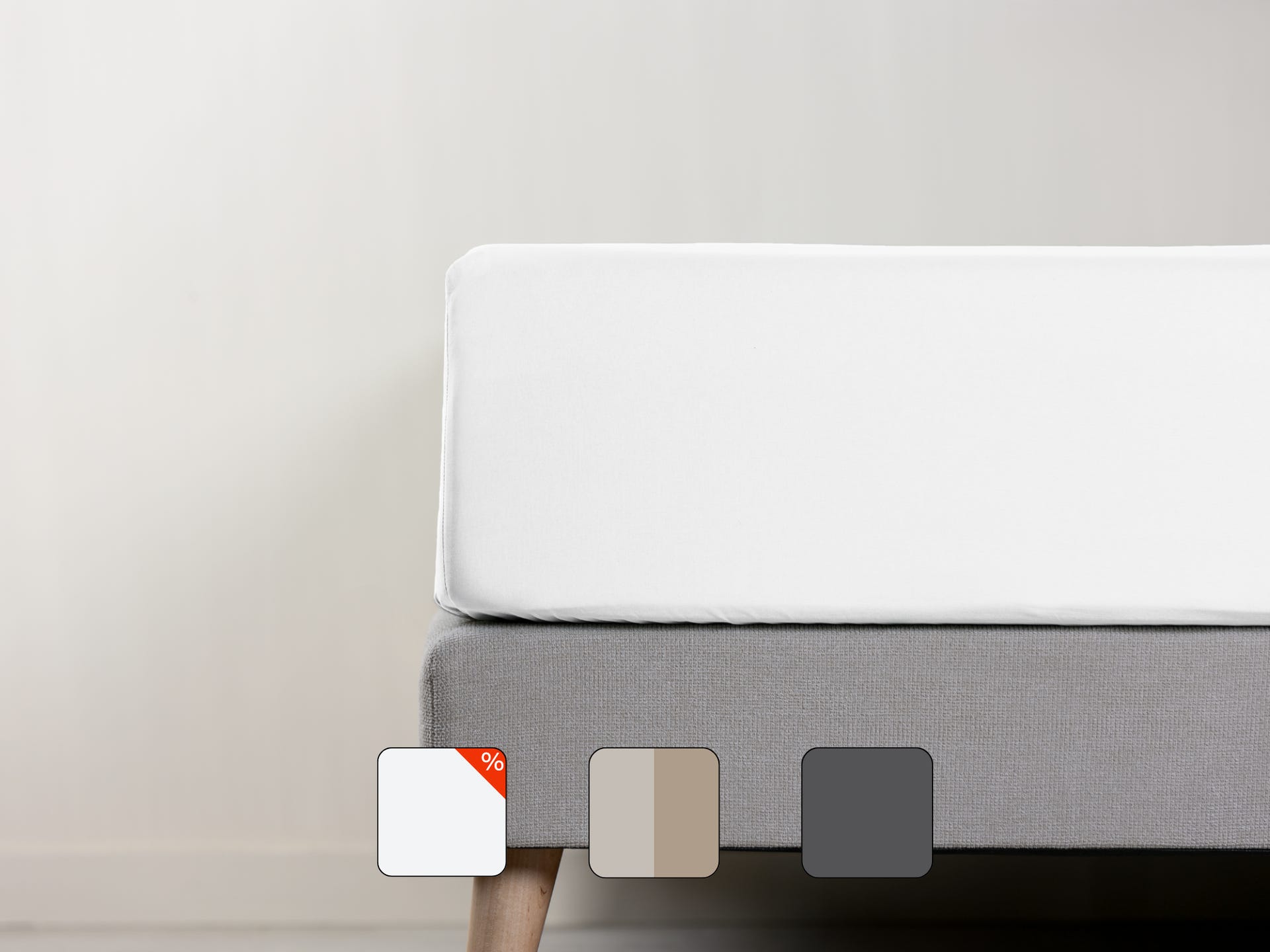 Uma imagem de um lençol de baixo em percal, em branco, sob um colchão com fundo cinzento