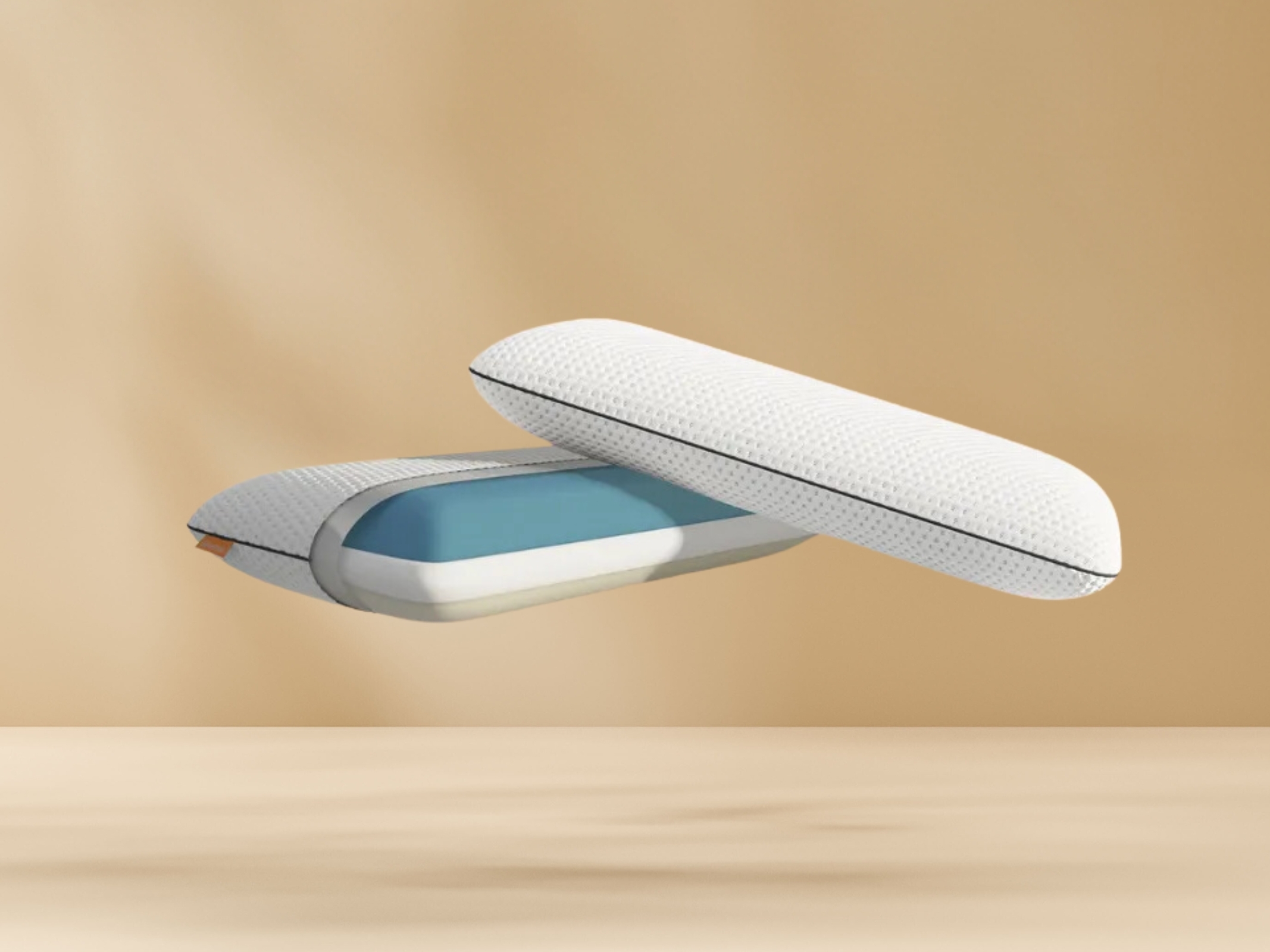 Twee witte Emma kussens met zwarte rits en blauwe binnenlaag zweven tegen beige achtergrond boven houten ondergrond; één kussen deels geopend, toont binnenstructuur van schuim.