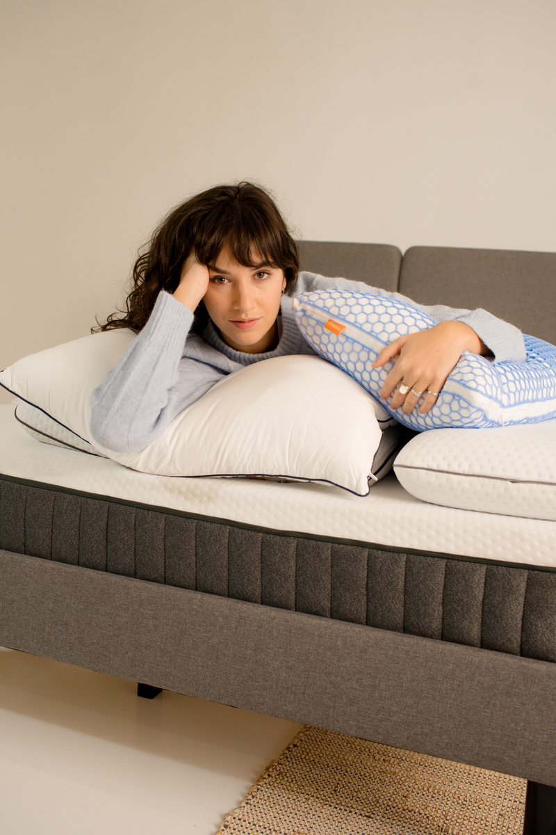 Woman laying on a mattress and holding a pillow.