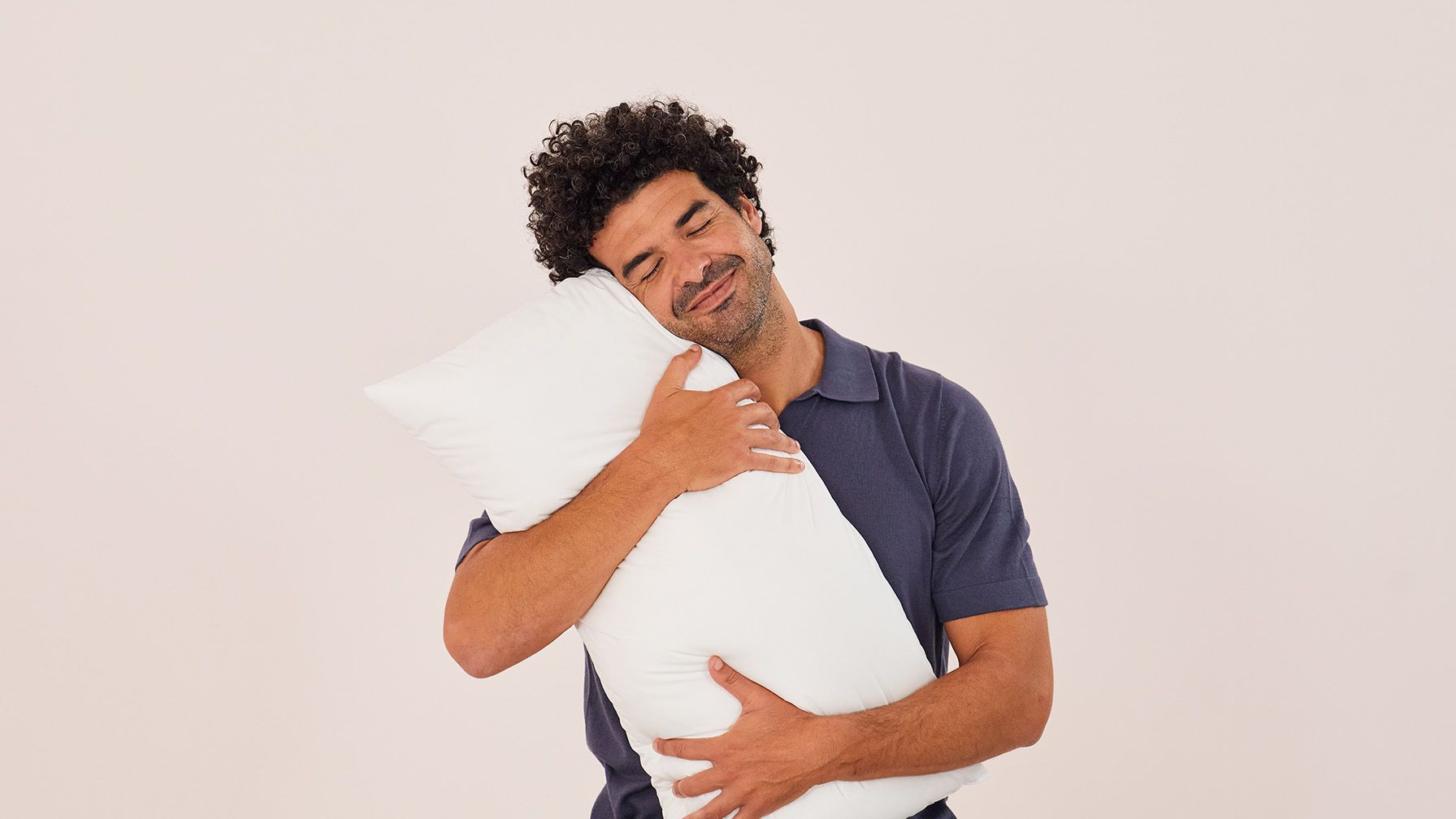 Mann umarmt zufrieden ein weißes Emma Kissen.