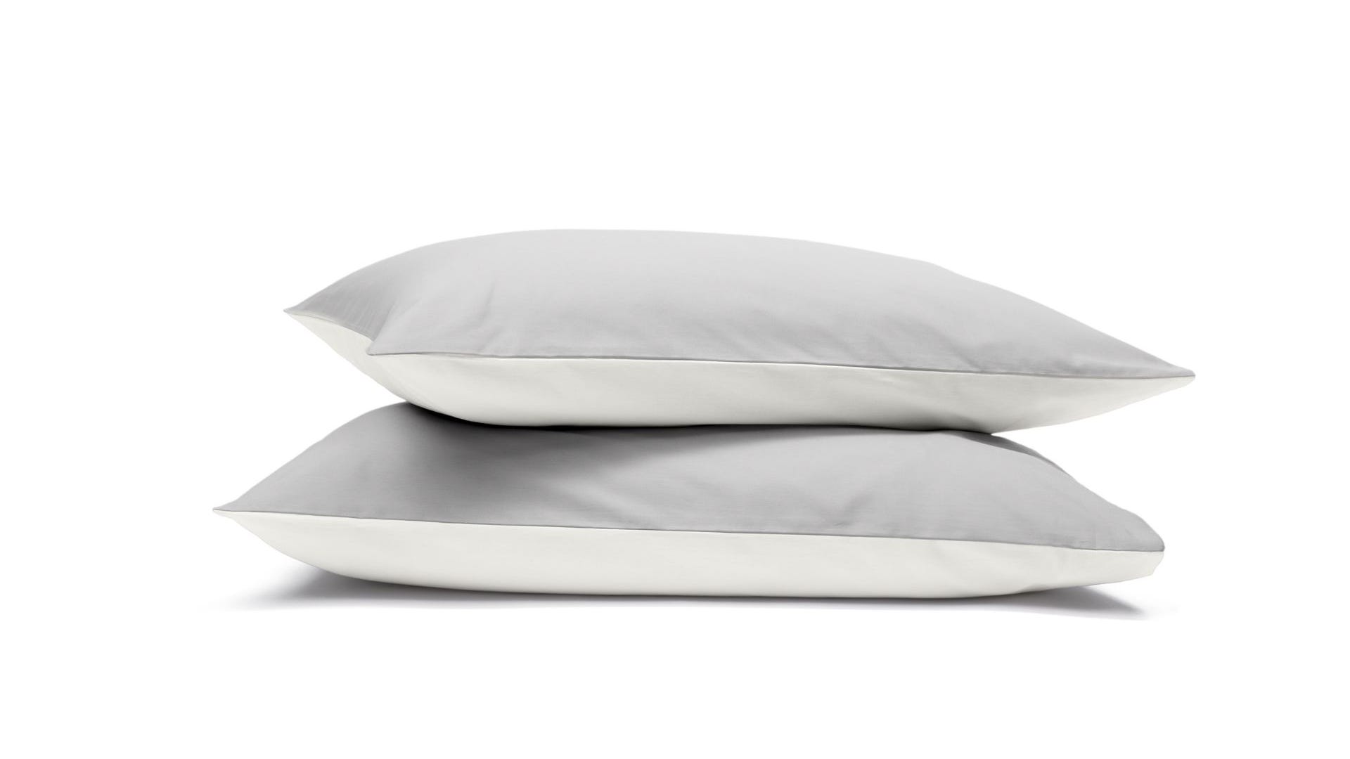 Due federe grigie e bianche impilate su sfondo bianco.