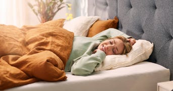 Mujer durmiendo en una cama tapizada Emma, premiada  por su calidad