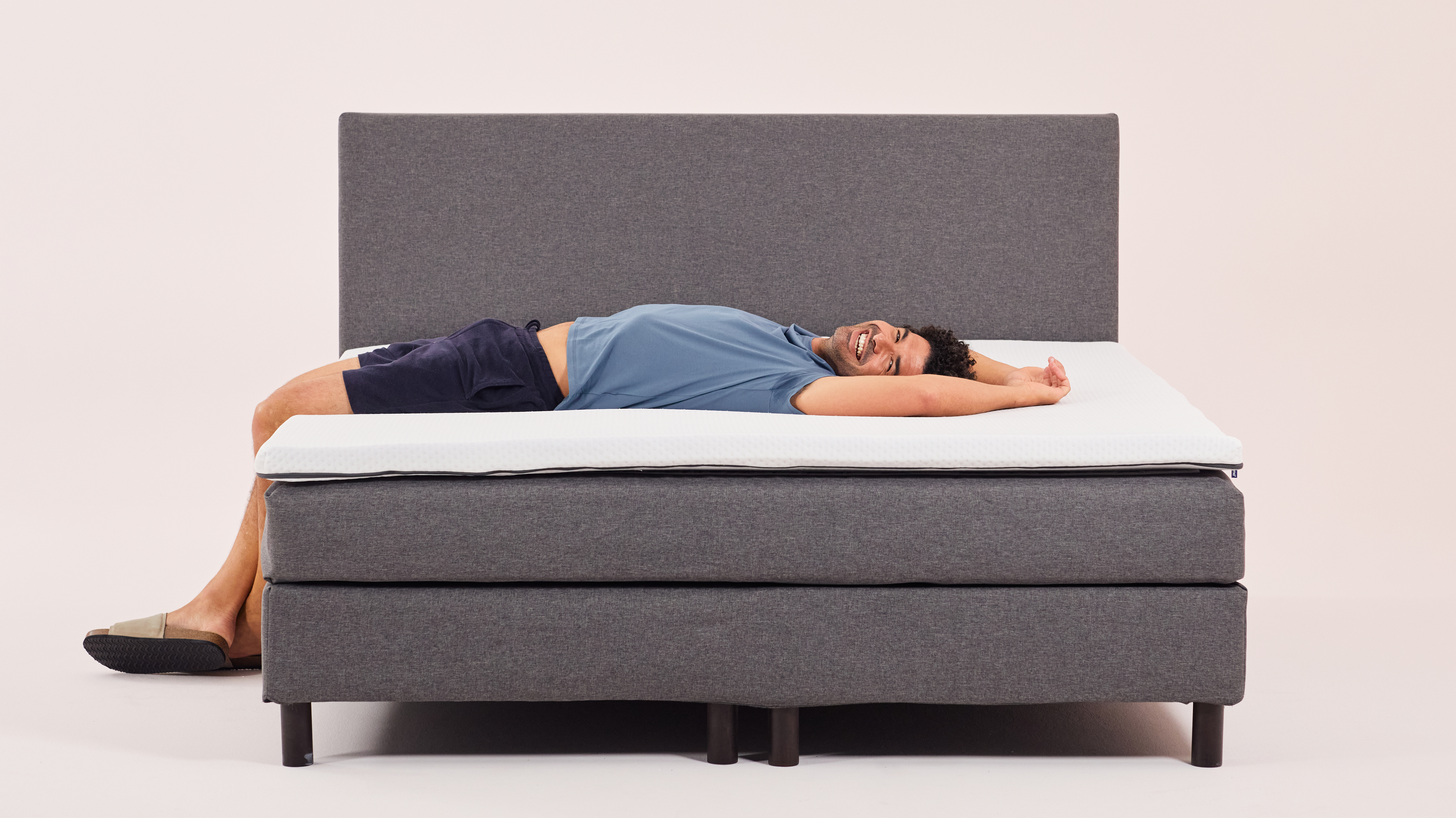 Man lying stretched on Emma topper, demonstrating full-body comfort and flexibility.