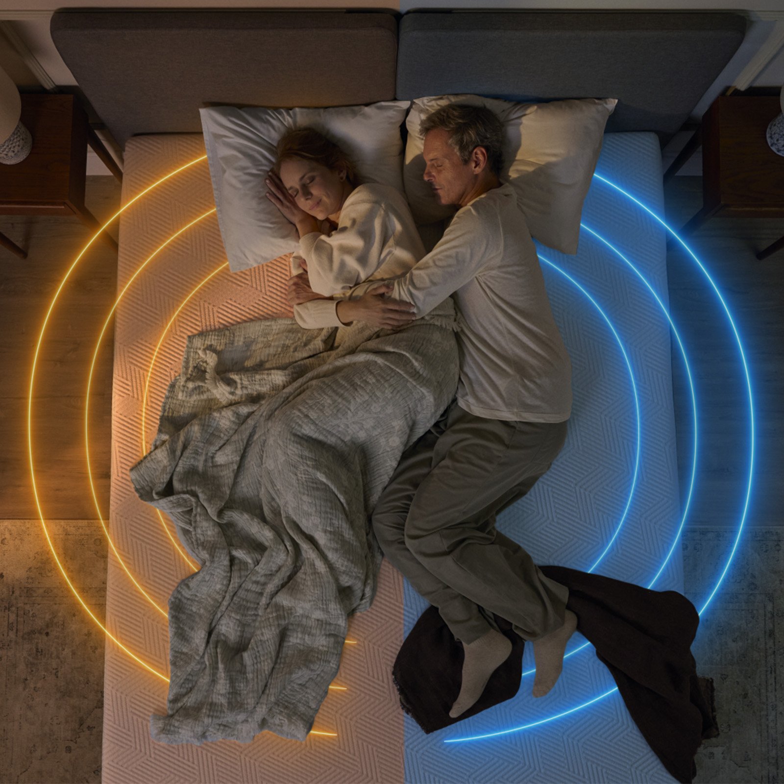 Couple sleeping on a mattress with warm and cool lighting shown on each side.