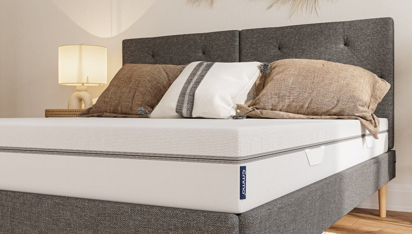Emma Matratze auf grauem Bett mit braunen und weißen Kissen.