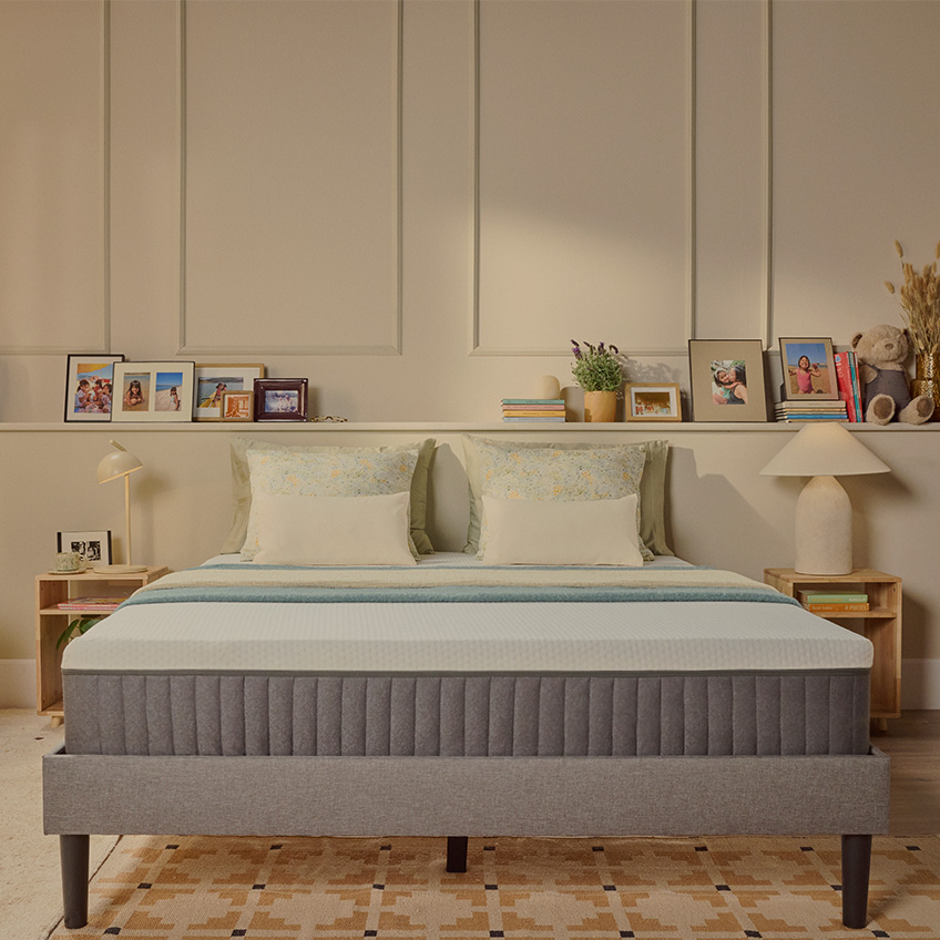 Colchão Emma Original com capa acolchoada branca sobre uma estrutura de cama cinzenta, num ambiente de quarto acolhedor.
