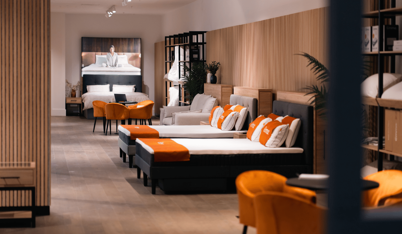 Emma Store Innenansicht mit ausgestellten Betten, Matratzen und orangefarbenem Sitzbereich.