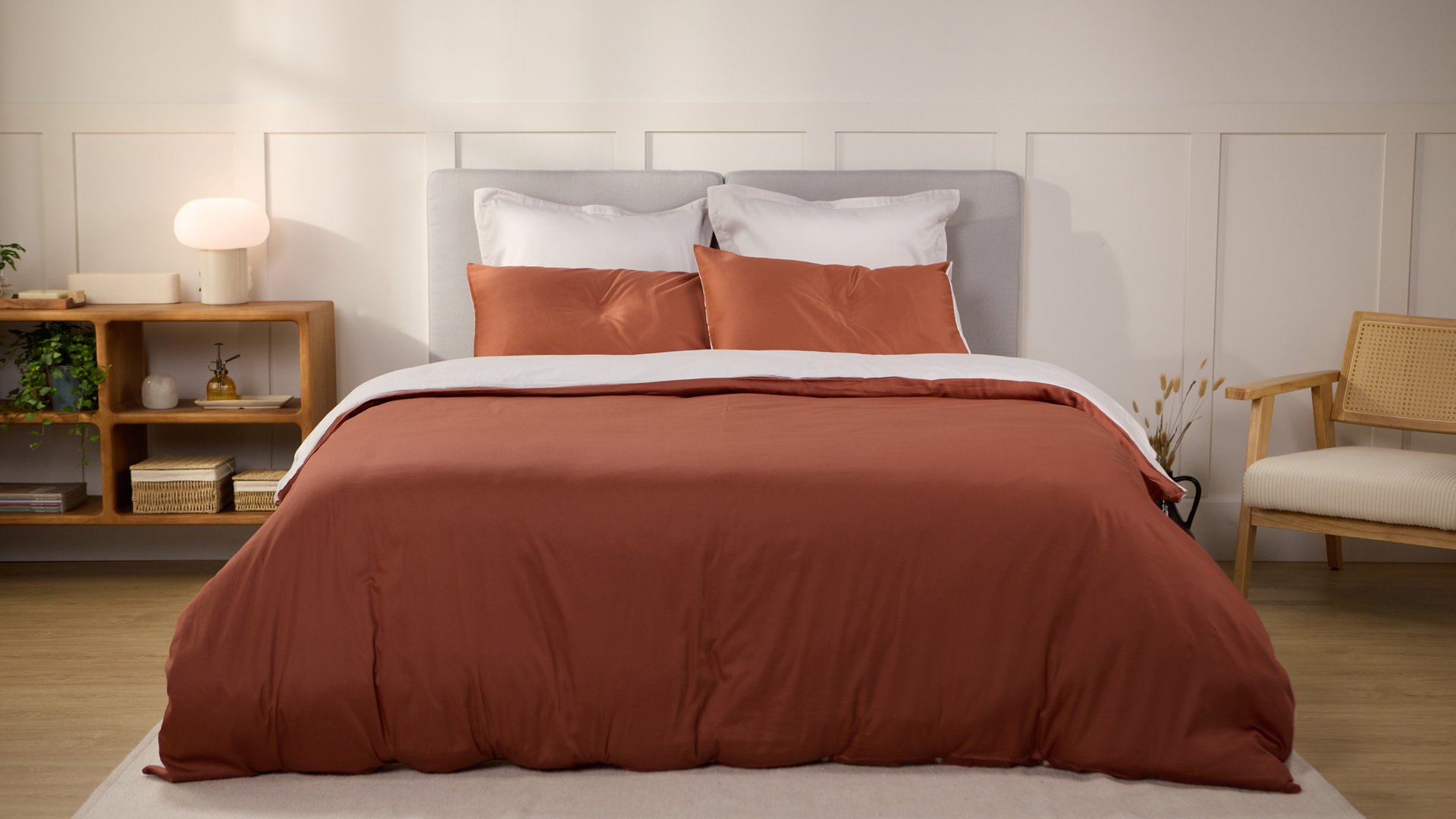Lit avec une housse de couette terracotta et des oreillers assortis.
