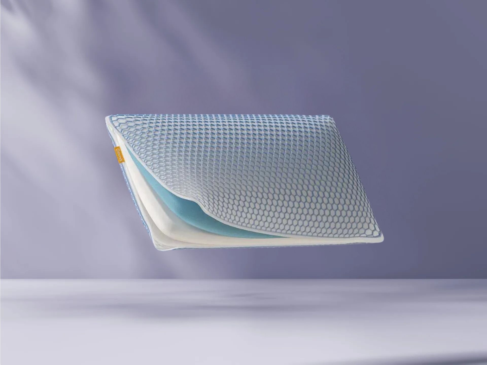 AirGrid® Adapt Kussen op paarse achtergrond, zichtbaar in profiel met hexagonaal patroon, witte en blauwe lagen en geel merklabel.