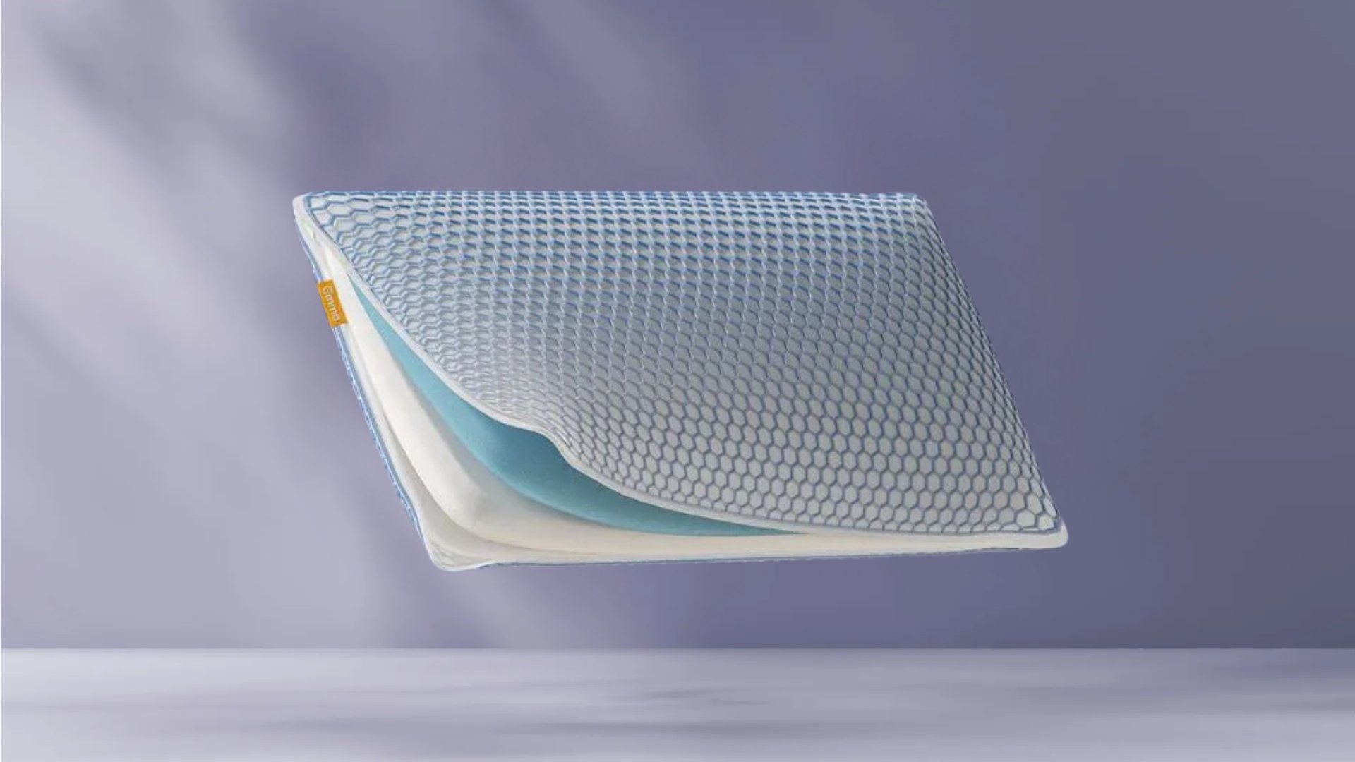 AirGrid® Adapt Kussens op paarse achtergrond, zichtbaar in profiel met hexagonaal patroon, witte en blauwe lagen en geel merklabel.