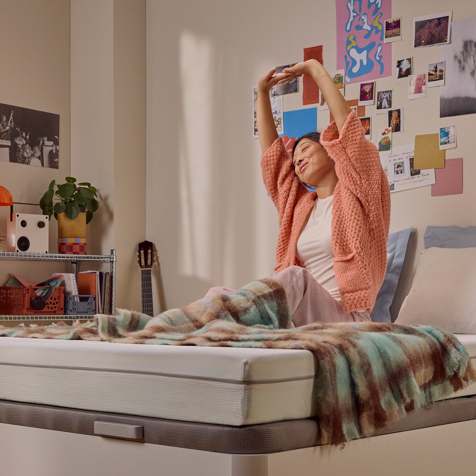 Person sitting up on a bed with a white mattress in the morning.