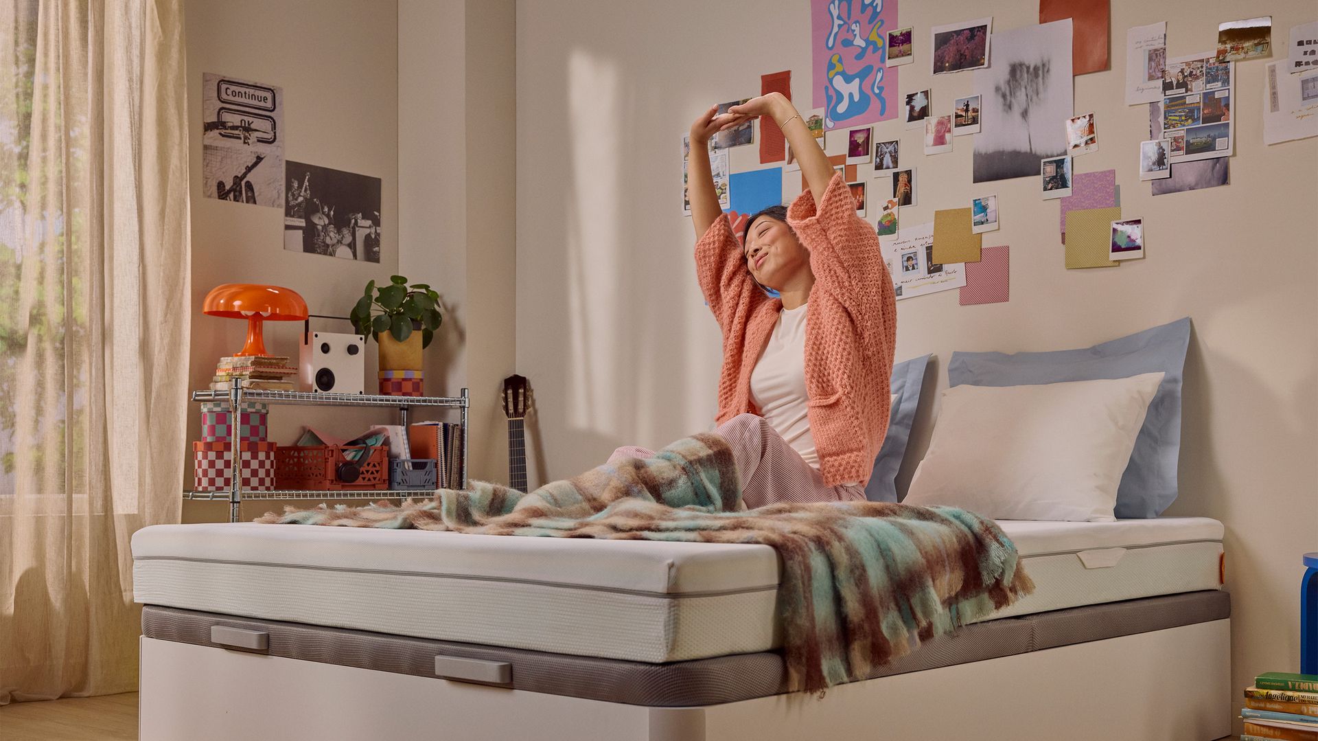 Person sitting up on a bed with a white mattress in the morning.