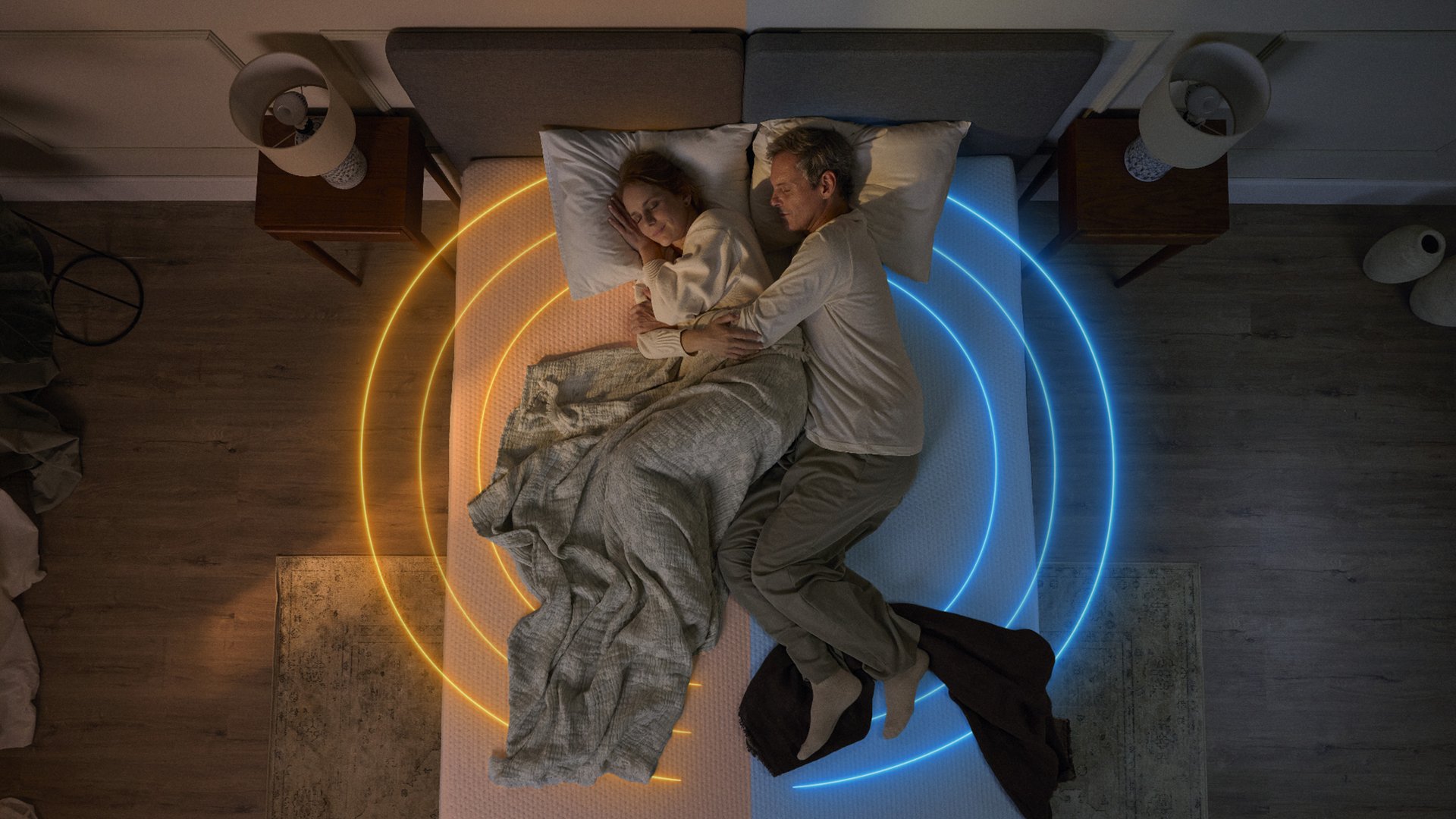 Pareja durmiendo en un colchón con iluminación cálida y fría en cada lado.