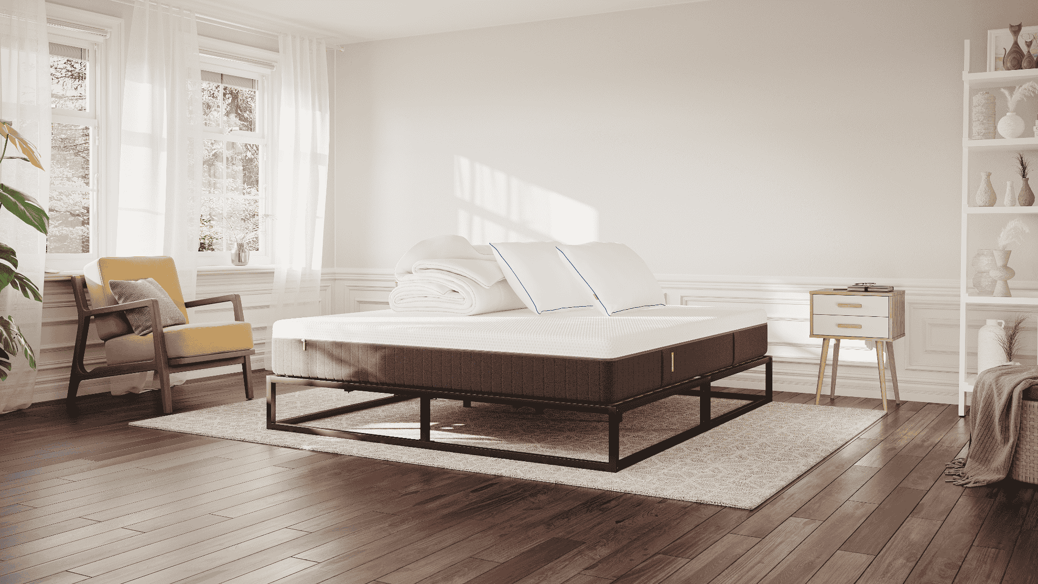 Licht en modern ingerichte slaapkamer met een Emma metalen bed, witte lakens, twee kussens en een opgevouwen dekbed; zachte natuurlijke lichtinval.