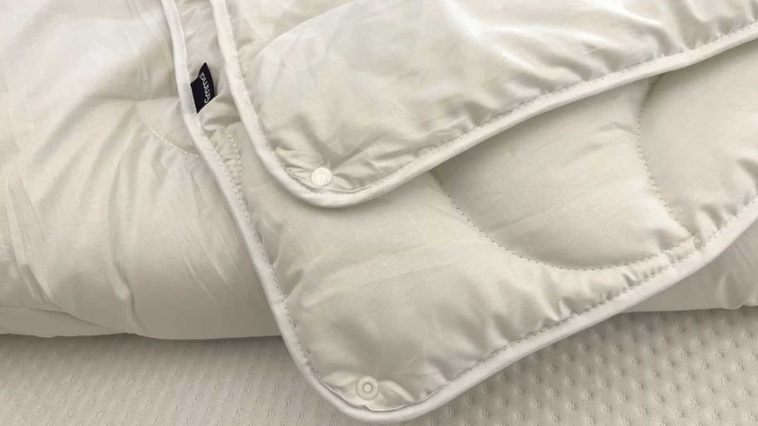 Gros plan des boutons permettant de combiner les couches de la couette, avec un logo Emma.