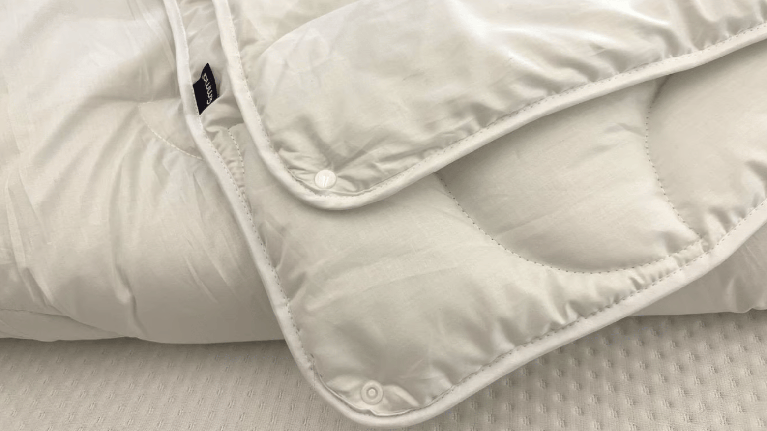 Gros plan des boutons permettant de combiner les couches de la couette, avec un logo Emma.