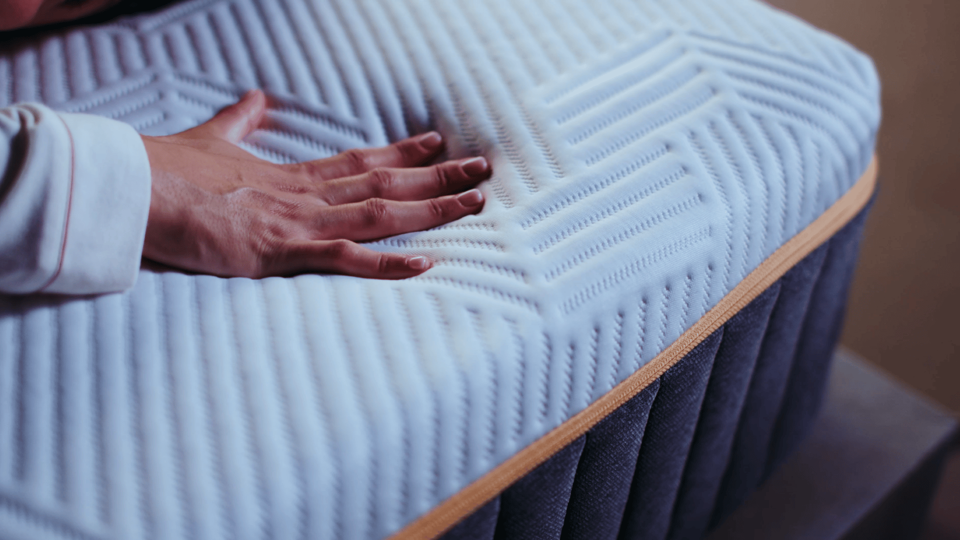 Hand drückt auf die weiche Oberfläche einer Elite Matratze mit strukturierter Textur.