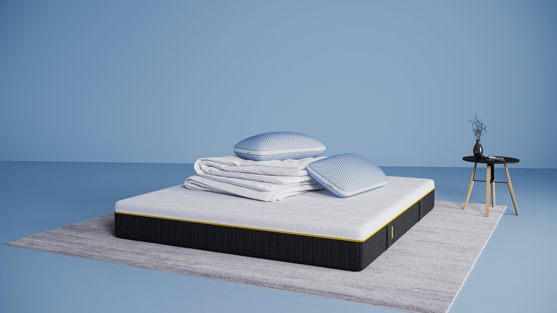 Emma AirGrid Deal Plus: Emma AirGrid Matras Plus, opgevouwen Emma dekbed (winter/herfst) en twee Emma AirGrid kussens, in een moderne slaapkameropstelling.