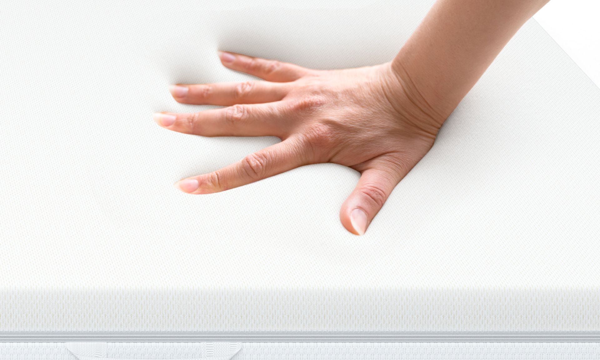 Mano che preme su superficie in memory foam bianca