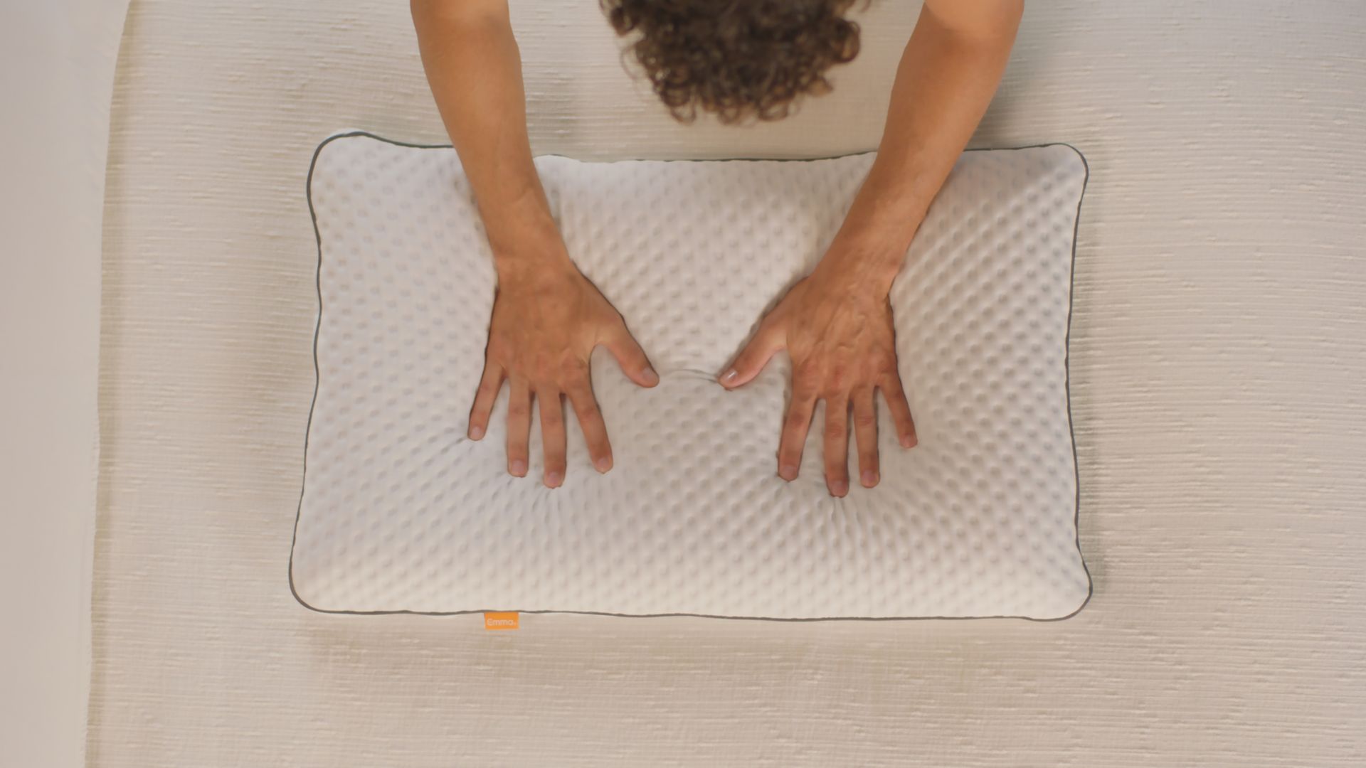 Personne appuyant sur l’Oreiller Original Premium à surface texturée et bordures foncées.