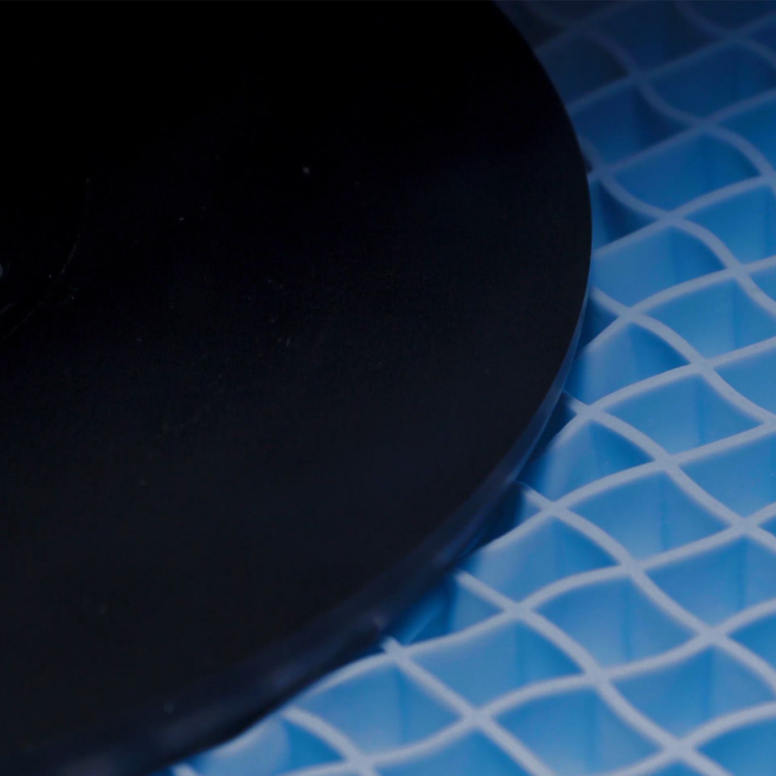 Weight pressing into blue grid foam layer showing pressure distribution on the mattress.