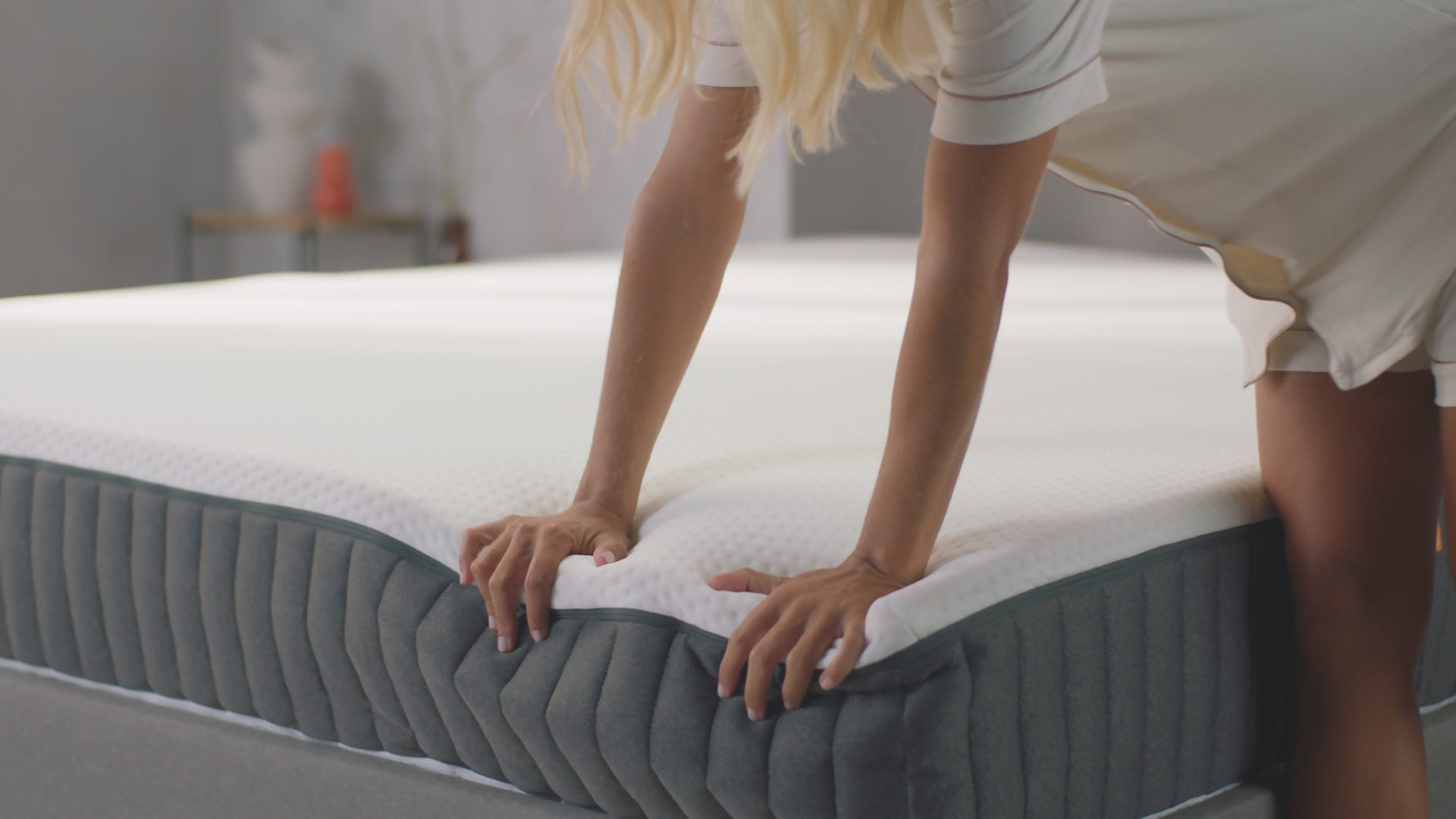 Handen die op de Emma Hybrid II matras drukken in een slaapkamer
