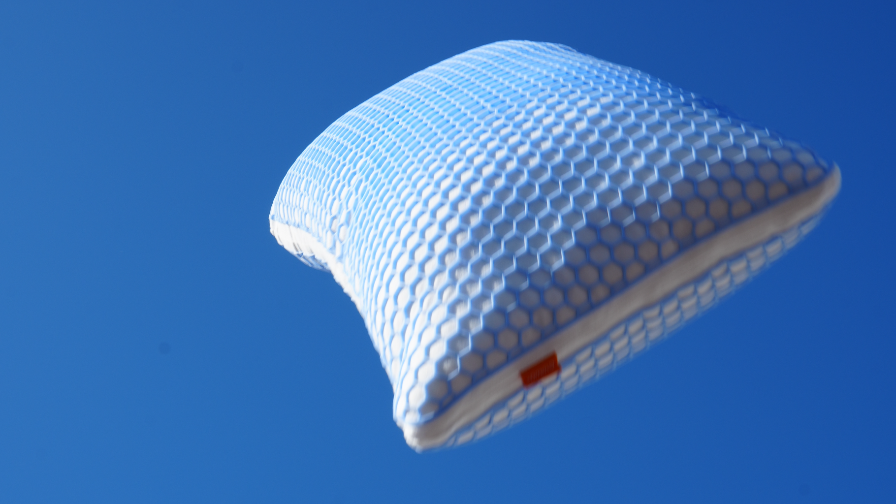 Ergonomisches Elite Kissen mit Wabenstruktur schwebt vor blauem Himmel.