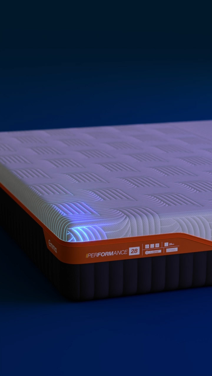 Close up of the corner of an Emma Performance 28 mattress with glowing blue light highlighting the grid pattern and orange border.