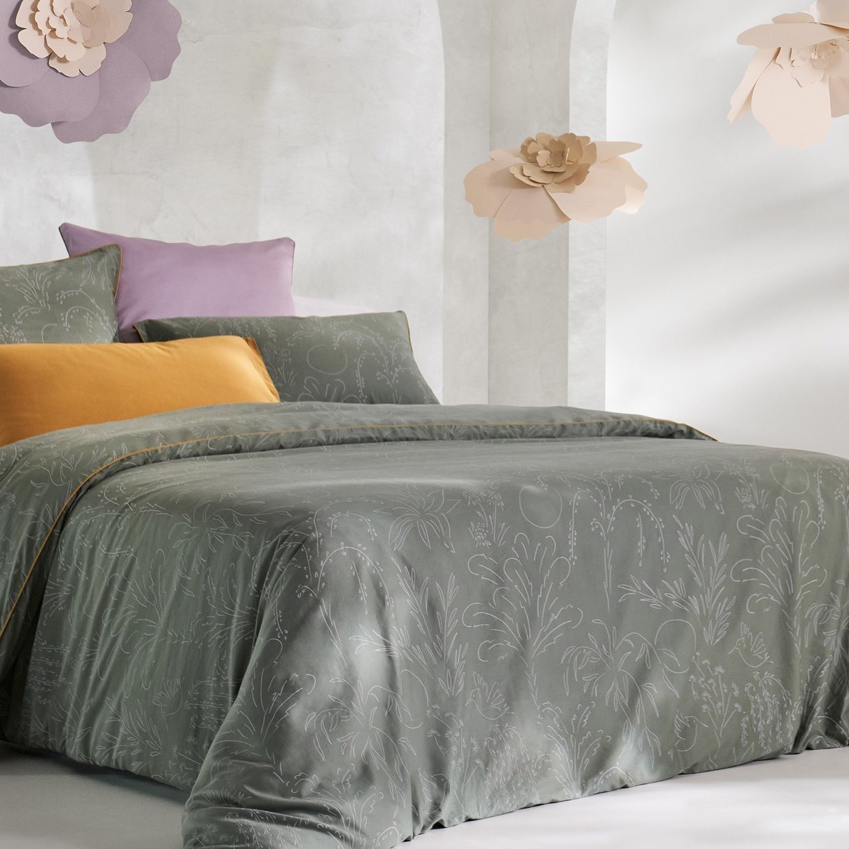 Vue de face d’une chambre décorée, avec un lit doté d’une couette colorée et de taies d’oreiller.