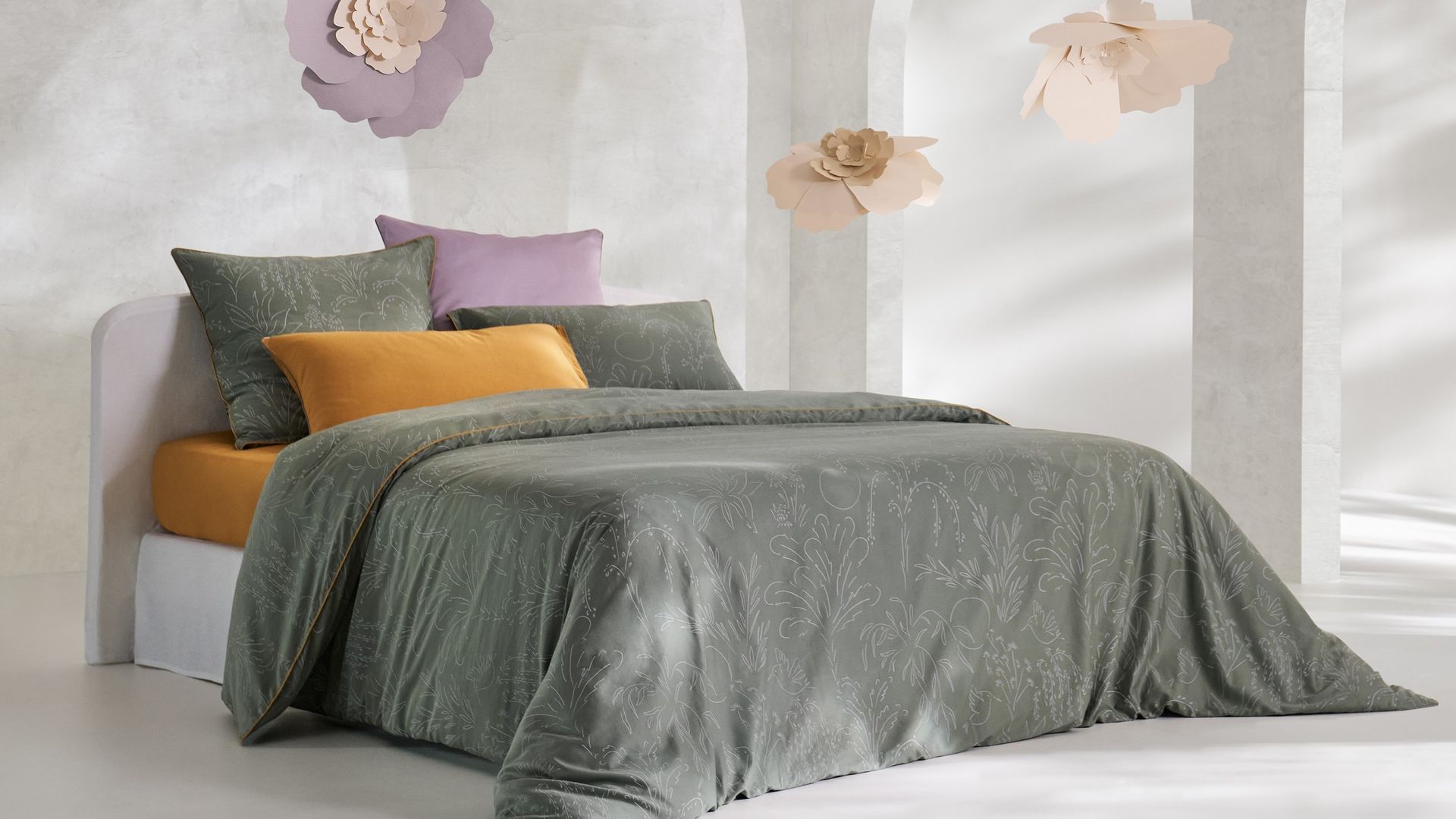 Vue de face d’une chambre décorée, avec un lit doté d’une couette colorée et de taies d’oreiller.