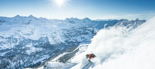 Skifahrer vor verschneiter Bergkulisse in Obertauern bei Sonnenschein.