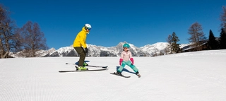 Zwei Skifahrende auf der Piste in der Region Seefeld vor verschneiten Bergen.