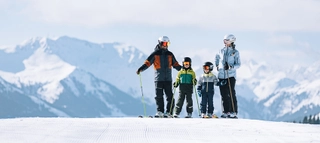 Zwei Erwachsene und zwei Kinder auf Ski im Skicircus Saalbach Hinterglemm Leogang Fieberbrunn.