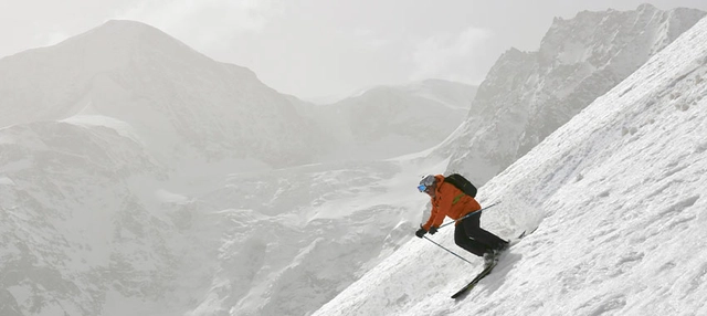 Aufnahme eines Skifahrers mit leicht vernebelter Bergkulisse im Hintergrund.