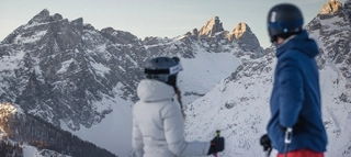 Zwei Skifahrer mit Blick auf verschneite Berge in Südtirol.