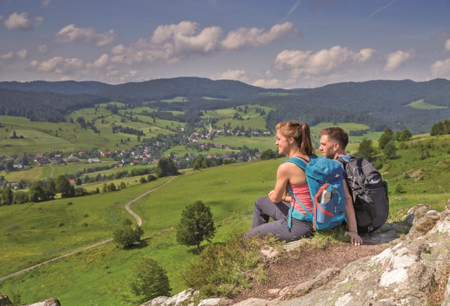 2.png Zwei Personen sitzen auf einem Stein und schauen in ein grünes Tal