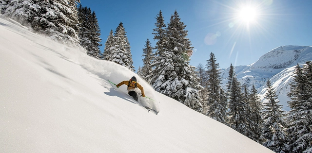 Skifahrer bei Abfahrt im Tiefschnee bei Sonnenschein im SalzburgerLand.