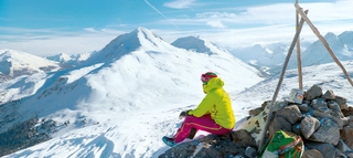 Person genießt Ausblick auf die schneebedeckten Berge in ValMüstair.