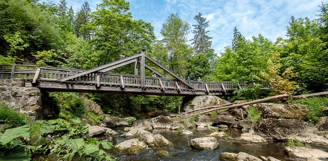 Große Brücke über steiniges Bachbett eines Flusses im Wald.