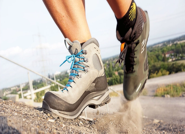 Zwei verschiedene Bergschuhe während des Aufstiges auf erdigen Untergrund.