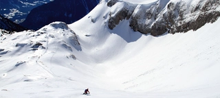 Skifahrer bei der Abfahrt in weißem Schneefeld