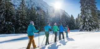 Winterwandernde vor verschneiter Baum- und Bergkulisse im Karwendel.
