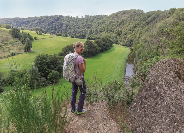 Die Autorin auf einem Wanderweg vor einem Ausblick auf einen Wald